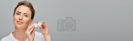 joyous beautiful woman with blonde hair holding contact lenses and looking at camera happily, banner