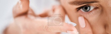 Photo for Beautiful woman in white comfy bathrobe wearing her contact lenses near mirror in bathroom, banner - Royalty Free Image