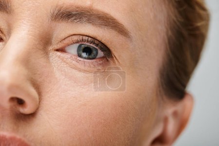 primer plano de mujer atractiva con el pelo rubio mirando a la cámara con lente de contacto en el ojo