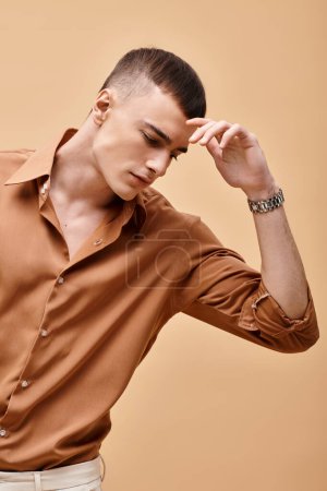 Porträt eines jungen, gut aussehenden Mannes im beigen Hemd, der auf pfirsichfarbenen beigen Hintergrund herabblickt