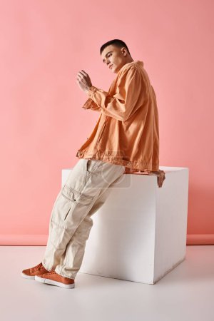 Téléchargez les photos : Image pleine longueur de l'homme élégant en chemise beige, pantalon et bottes sur fond blanc sur fond rose - en image libre de droit