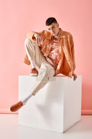 Foto de Foto de moda de hombre de moda en camisa beige, pantalones y botas en cubo blanco sobre fondo rosa - Imagen libre de derechos