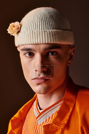 Foto de Retrato de hombre elegante en traje naranja con gorro beige con flor mirando a la cámara - Imagen libre de derechos