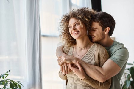 Couple in love of handsome man and curly woman at home in the morning, laughing and hugging