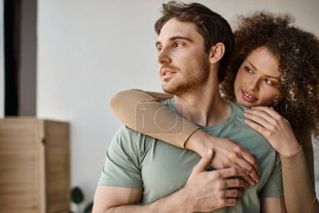 Affectionate morning embrace of a curly young woman and brunette man, holding hands tightly