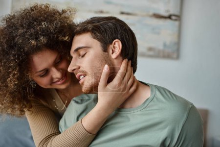 curly young woman and brunette man embrace lovingly, feeling the warmth of their bond