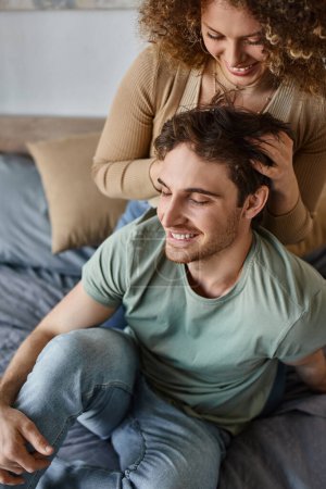 curly young woman massaging boyfriends head cherishing their moment together