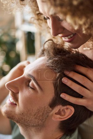 Téléchargez les photos : Gros plan de frisée jeune femme massant doucement les copains tête souriant ensemble - en image libre de droit