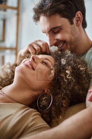 Téléchargez les photos : Gros plan de jeune femme bouclée couchée avec son petit ami souriant et riant ensemble - en image libre de droit