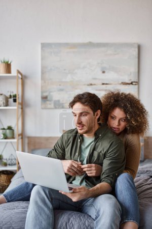 Preciosa pareja joven pasar tiempo juntos en la cama con el ordenador portátil y ver películas
