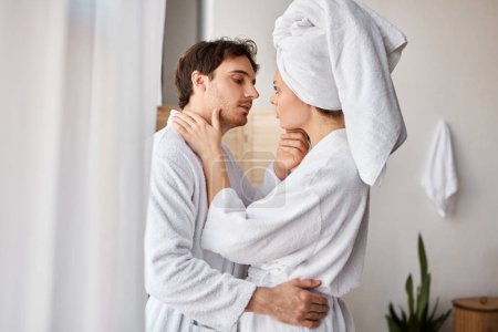 Attraktives verliebtes Paar im Badezimmer, das sich umarmt und kuschelt, Mann berührt seine Freundin in der Taille