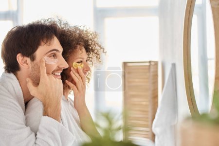 Photo for Portrait of happy couple with eye patches  looking in the mirror and smiling together - Royalty Free Image
