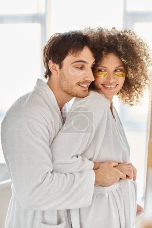 Porträt eines glücklichen Paares mit Augenklappen, das sich im Badezimmer umarmt und zusammen lächelt