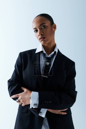 Eine junge Afroamerikanerin Mitte 20 posiert selbstbewusst in Anzug und Krawatte für ein Foto.