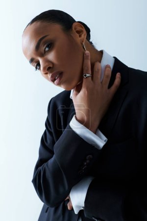 Young African American woman in her 20s wearing a black suit and white shirt.