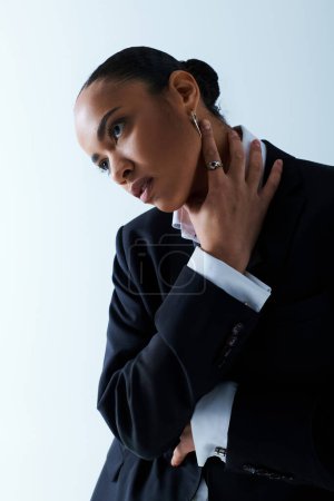 Foto de Joven mujer afroamericana de unos 20 años con un traje negro afilado y una camisa blanca crujiente. - Imagen libre de derechos