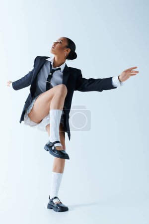 African American woman in 20s in a suit and tie dancing energetically in a studio.