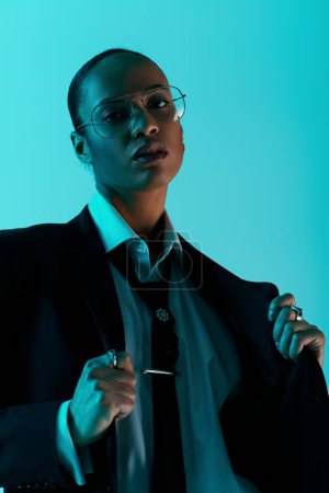 young African American woman in a suit and tie strikes a confident pose in a studio setting.