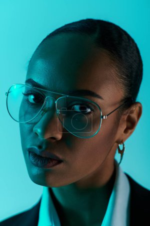 Une jeune afro-américaine avec des lunettes et une chemise blanche pose en toute confiance en studio