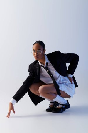 A young African American woman in a suit and tie gracefully kneels down