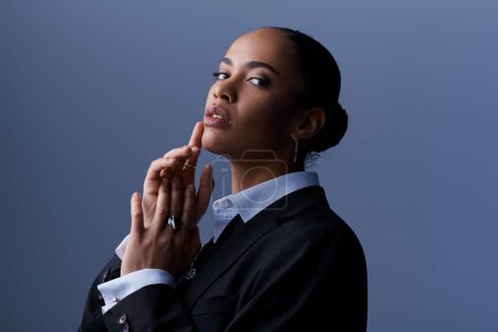 Eine junge Afroamerikanerin im Businessanzug hält elegant ihre Hände zusammen.