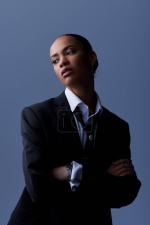 Una joven afroamericana posa confiadamente en un traje y corbata para un retrato en un ambiente de estudio.