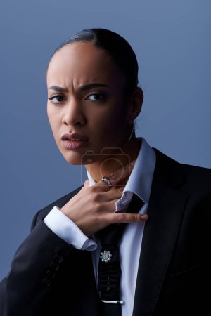 Young African American woman confidently poses in a stylish suit and tie.