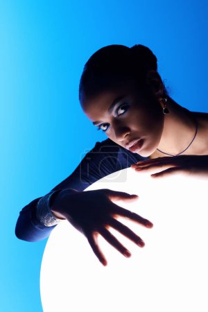 Photo for Young African American woman with hands on a round object, connecting with energy. - Royalty Free Image