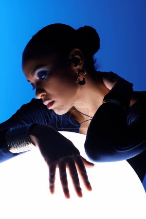 Téléchargez les photos : Une jeune Afro-Américaine pose délicatement ses mains sur un objet lumineux - en image libre de droit