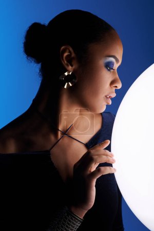 Téléchargez les photos : Jeune femme afro-américaine berçant délicatement une sphère blanche dans ses mains. - en image libre de droit