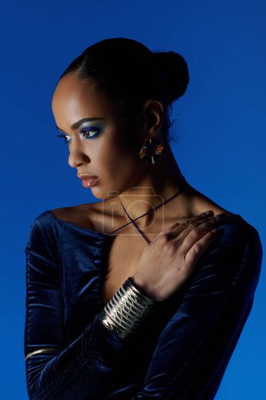 Young African American model in a flowing blue dress striking a pose in a studio setting.