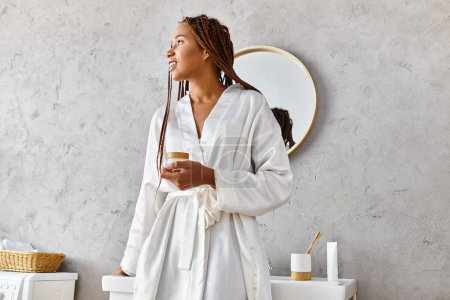 Eine afroamerikanische Frau mit Afro-Zöpfen steht anmutig in einem modernen Badezimmer und strahlt Schönheit und Gelassenheit aus.