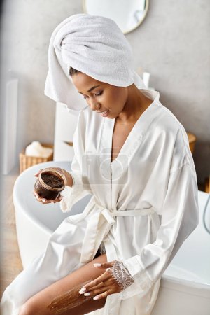 An African American woman in a bathrobe relaxes with a coffee scrub in her modern bathroom, embracing a moment of calm and beauty.