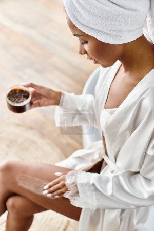 Photo for A woman in a white robe holding scrub in jar inside of modern bathroom - Royalty Free Image