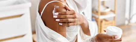 Téléchargez les photos : Une Afro-Américaine avec des tresses afro tenant une bouteille de lotion dans sa main dans une salle de bain moderne. - en image libre de droit
