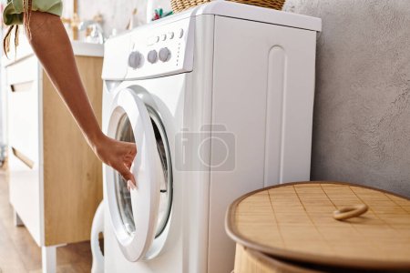 Femme afro-américaine installant une machine à laver dans une buanderie soignée avec carrelage et murs blancs.