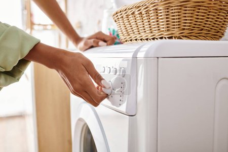 Eine Afroamerikanerin lädt in einem Badezimmer einen Trockner auf eine Waschmaschine.
