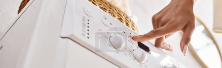 Photo for An African American woman pressing button on washing machine. - Royalty Free Image