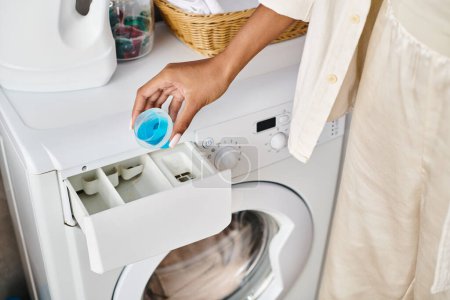Mujer afroamericana limpia una lavadora en un baño como parte de su rutina de tareas domésticas.
