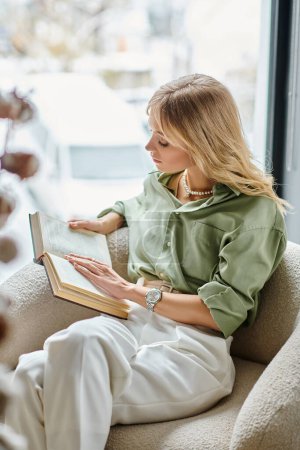 Frau sitzt im Stuhl, vertieft in ein Buch lesen.