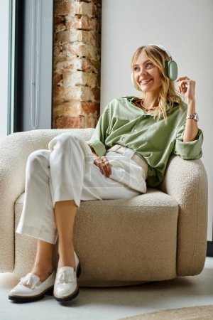 Téléchargez les photos : Une femme assise sur un canapé à côté d'une fenêtre dans un décor de maison ou d'appartement. - en image libre de droit