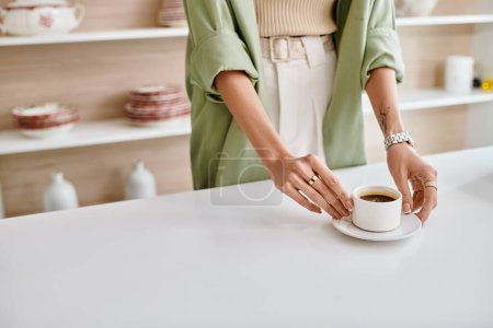Eine Frau steht in einer Wohnküche und hält eine Tasse Kaffee in der Hand.