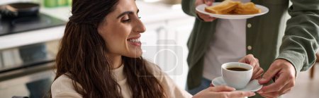 Photo for Cheerful disabled woman in wheelchair holding coffee next to her husband while in kitchen, banner - Royalty Free Image