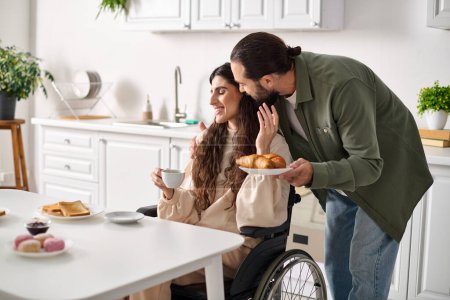 Téléchargez les photos : Gai belle femme handicapée en fauteuil roulant profiter du café avec son mari pendant le petit déjeuner - en image libre de droit