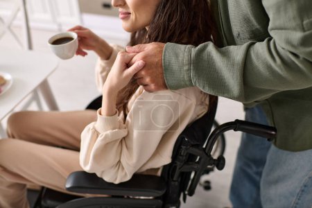 vista recortada de la alegre mujer discapacitada en silla de ruedas bebiendo café con su marido en el desayuno