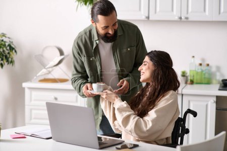 Photo for Handsome man in homewear offering coffee to his disabled hard working beautiful wife in wheelchair - Royalty Free Image