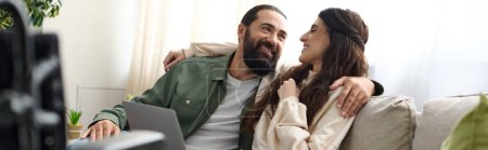Téléchargez les photos : Couple aimant de barbu homme et sa femme handicapée passer du temps ensemble à l'ordinateur portable sur le canapé, bannière - en image libre de droit