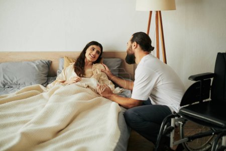 beautiful joyous woman with mobility disability lying in bed next to her bearded loving husband