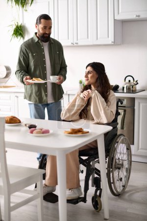 Foto de Barbudo hombre cariñoso trayendo a su alegre esposa con brindis por discapacidad y café caliente en el desayuno - Imagen libre de derechos