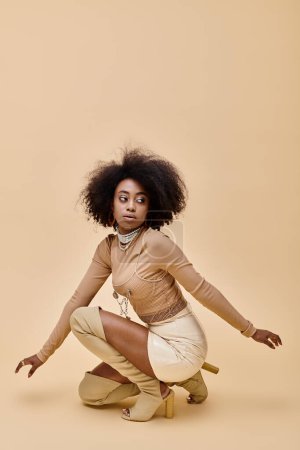young african american model in stylish pastel outfit and thigh-high boots sitting on a beige